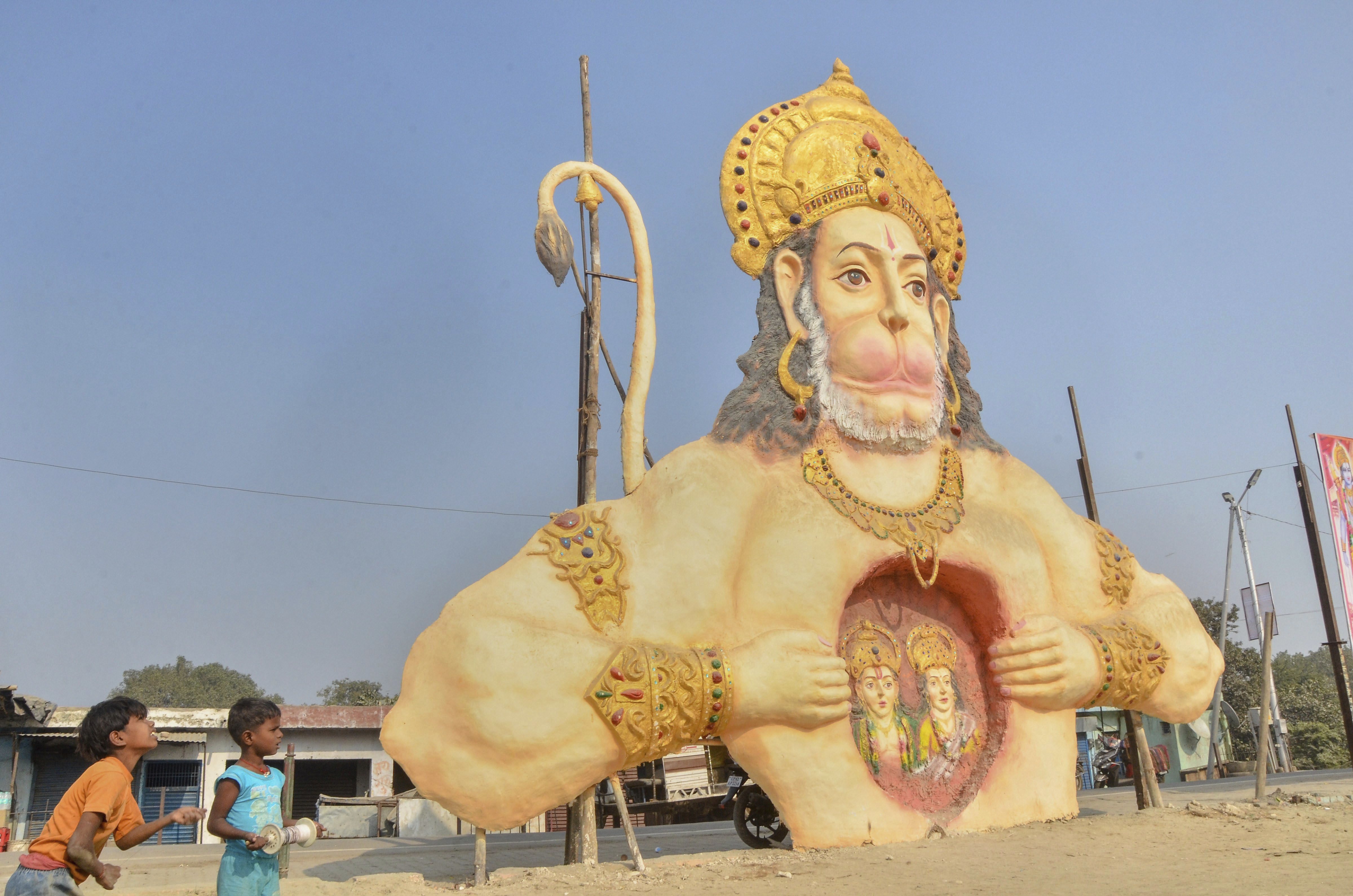 Boys fly kites near a giant statue of Lord Hanuman at a field in Ayodhya - PTI