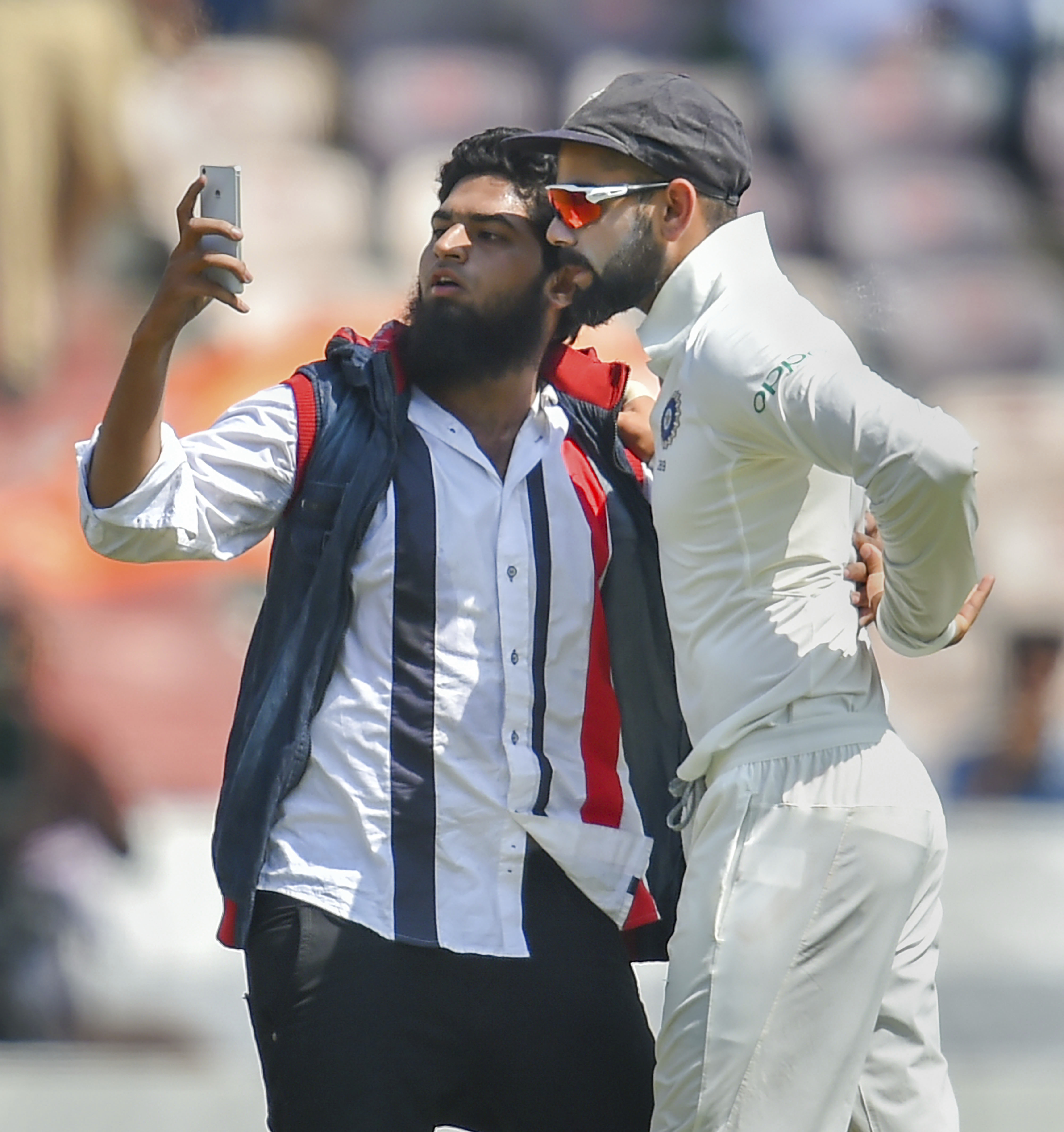 A pitch invader takes a selfie with Indian cricket captain Virat Kohli during the second test match between India and West Indies, in Hyderabad - AP