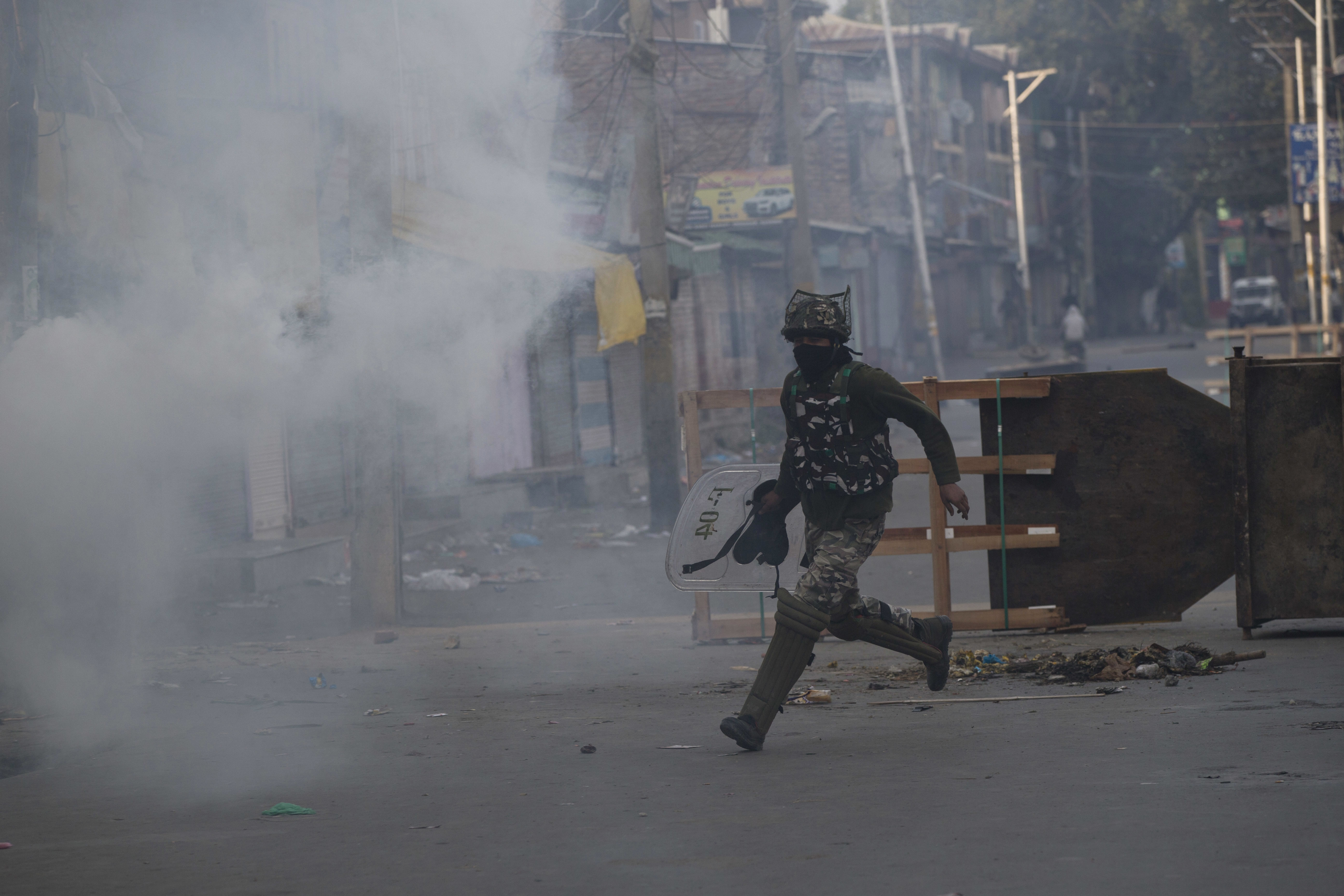 An Indian paramilitary soldier runs for cover during a protest in Srinagar - AP