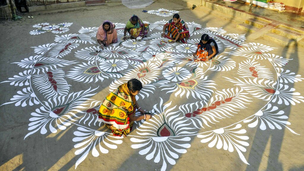 People paint rangolis outside their home ahead of Makar Sakranti festival, in Lankamura village on the outskirts of Agartala - PTI