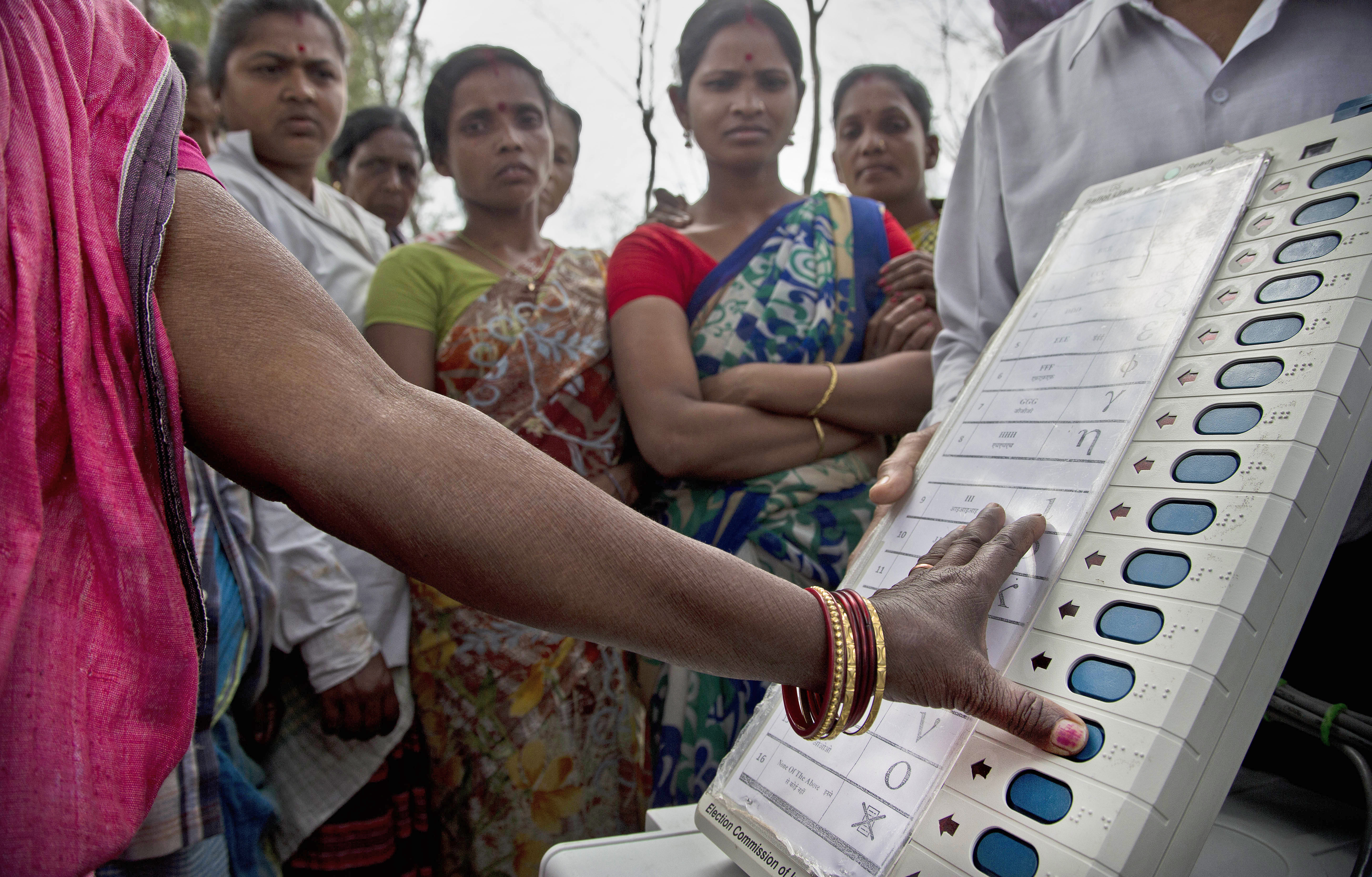 A woman casts her vote on the demo electronic voting machines and Voter Verifiable Paper Audit Trail or VVPAT during an election awareness drive by district administration amongst the tea garden laborers ahead of India's general election in Jorhat - PTI