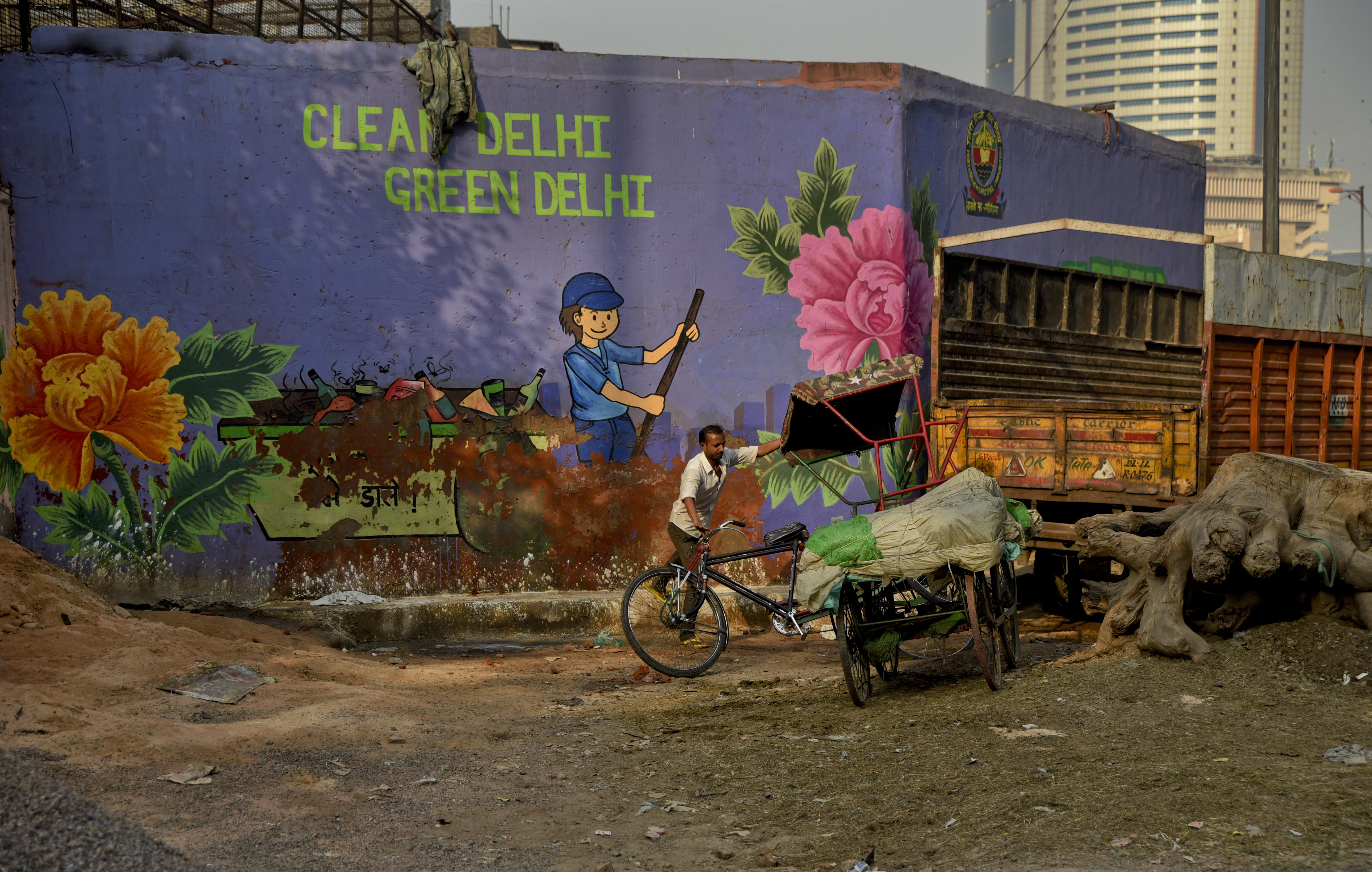 An Indian cycle rickshaw puller maneuvers his rickshaw past an awareness mural campaigning for a clean and green Delhi in New Delhi, India - AP