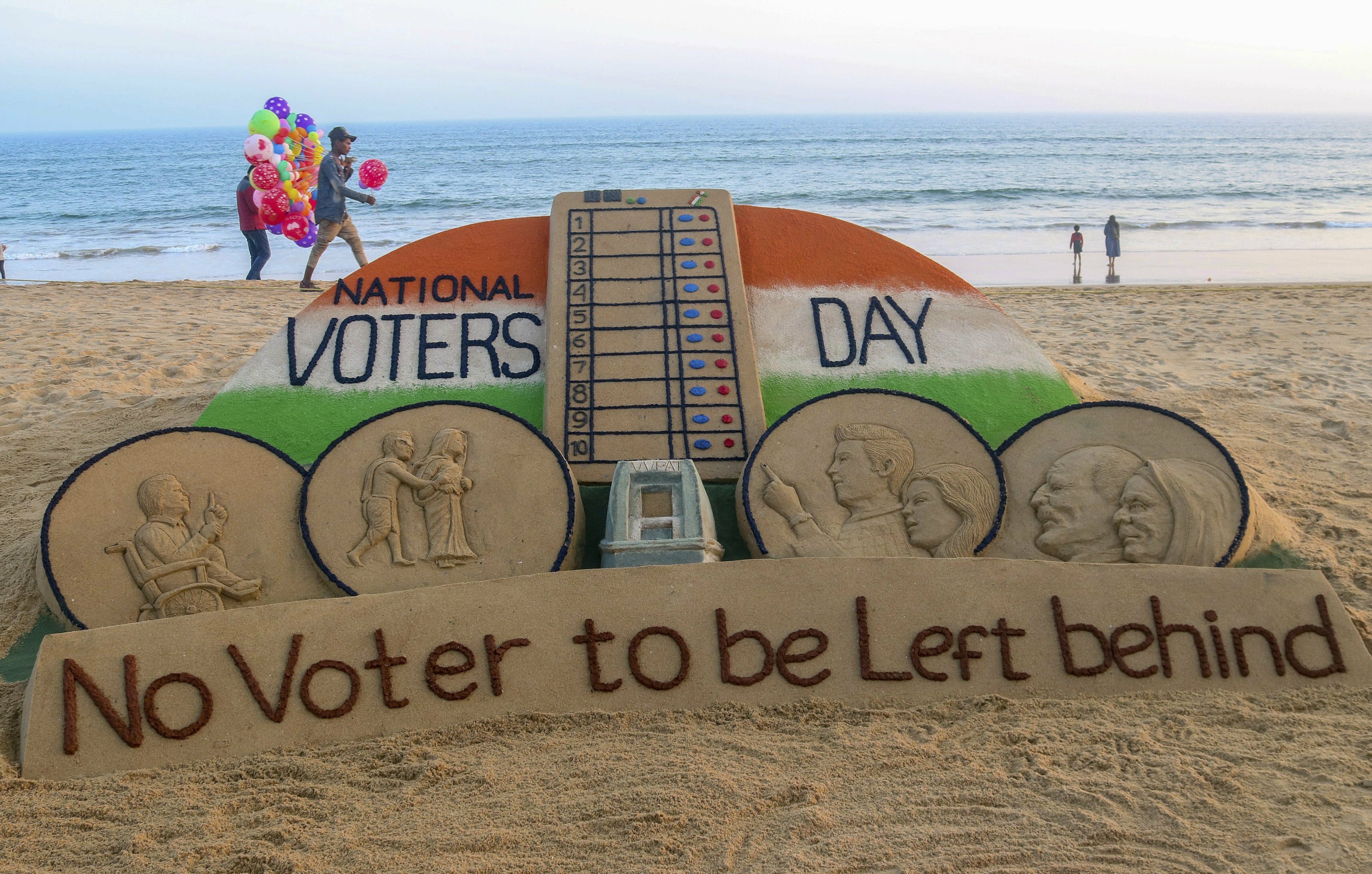 Sand artist Sudarsan Pattnaik creates a sand sculpture on the eve of National Voters' Day, at Puri beach in Puri - PTI