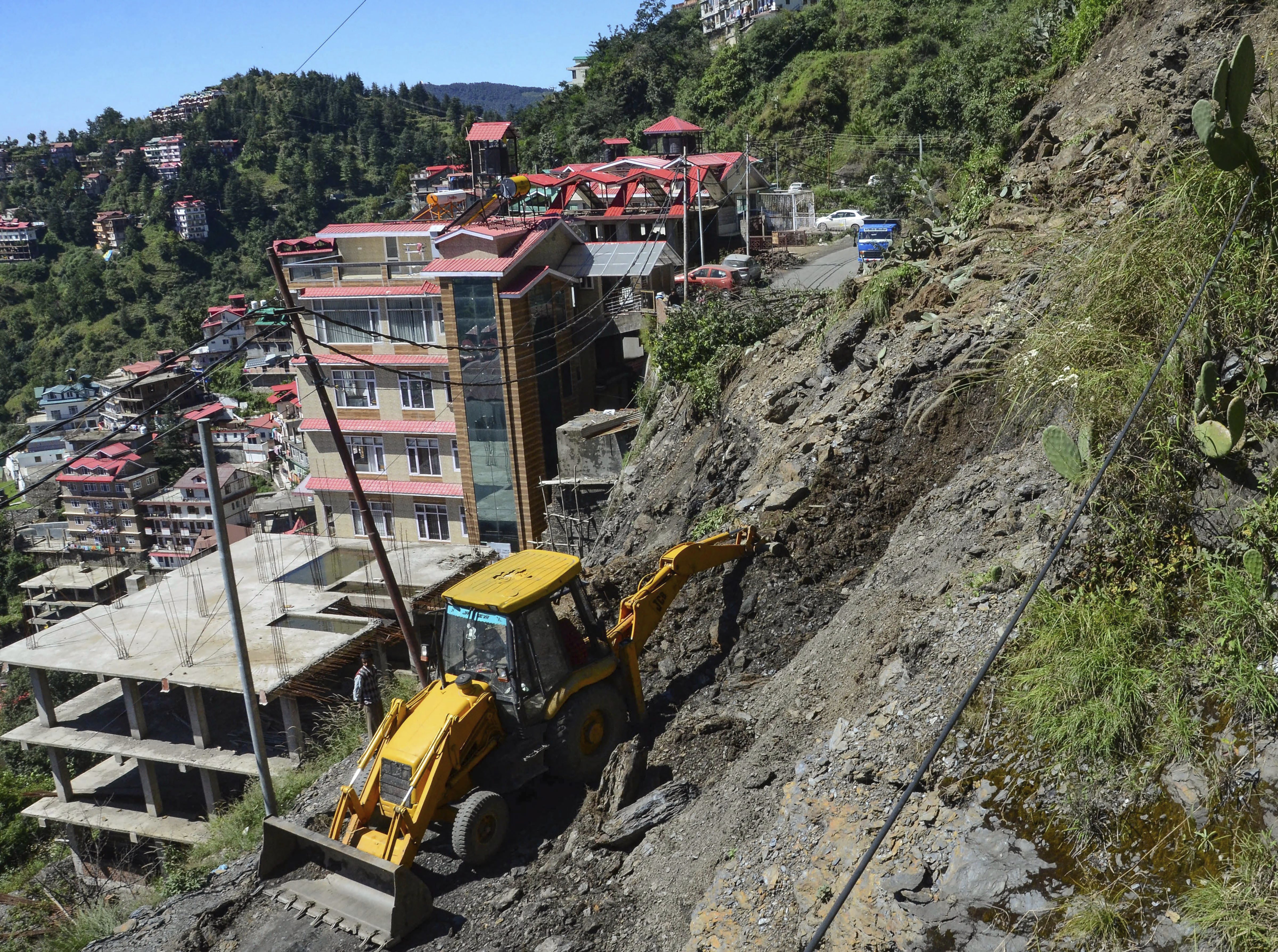 An earthmover clears debris from a road after a landslide triggered by incessant rains, in Shimla - PTI