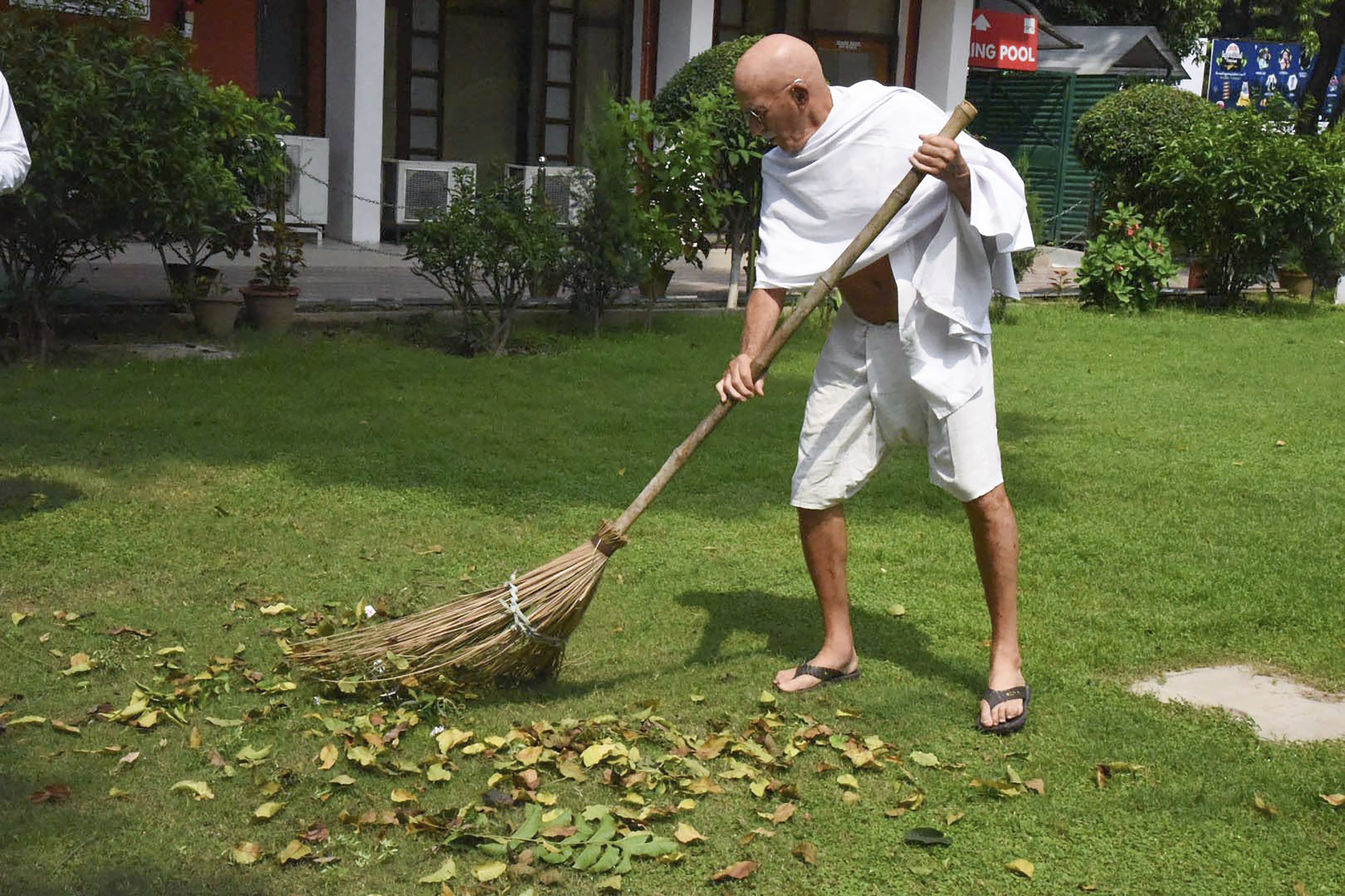 A man, dressed up like Mahatma Gandhi, sweeps a lawn ahead of Gandhi Jayanti in Chandigarh - PTI