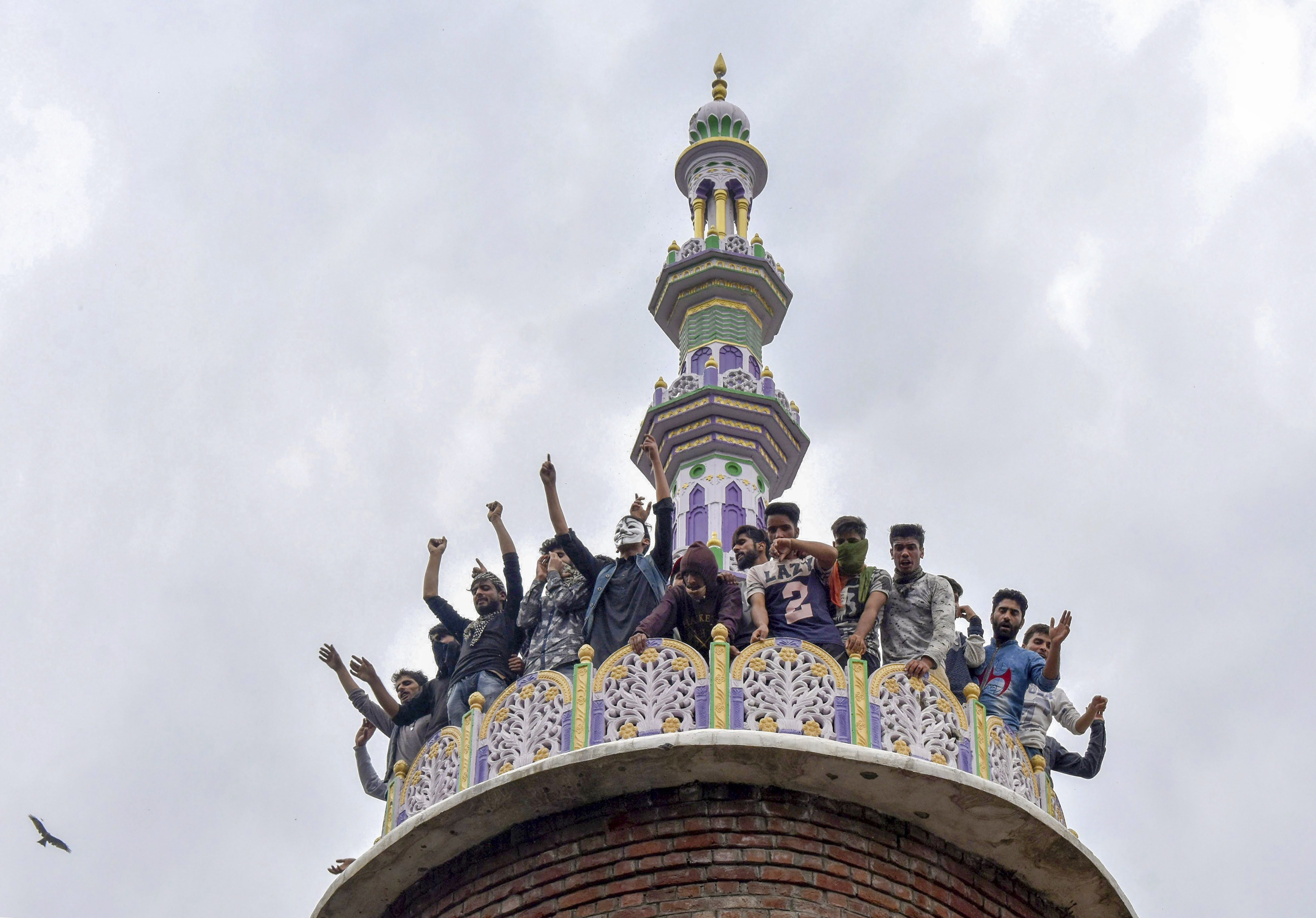 People raise slogans from the tomb of a mosque, where militants were hiding during an encounter with security forces, at Panzan Chadoora area of Budgam district near Srinagar - PTI