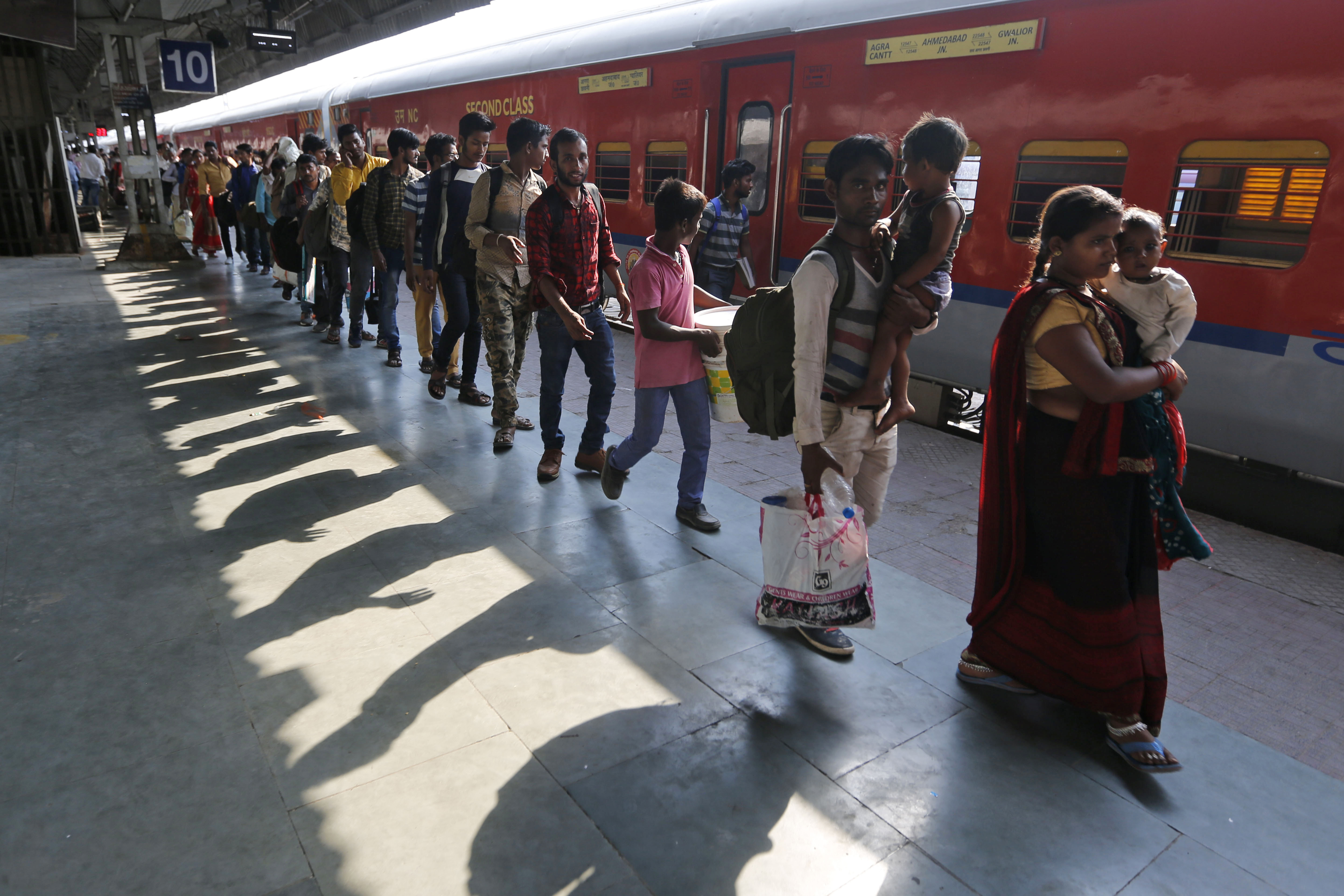 Indians walk in a queue to board a train to Uttar Pradesh, at a railway station in Ahmadabad, India - AP